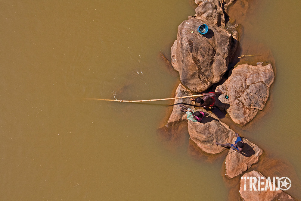 A bridge can be an excellent way to gain a stealth bird’s-eye view. These teenagers were unaware of the author’s presence without a buzzing drone overhead. They fished on large peach-colored rocks along a river in southern Mozambique.