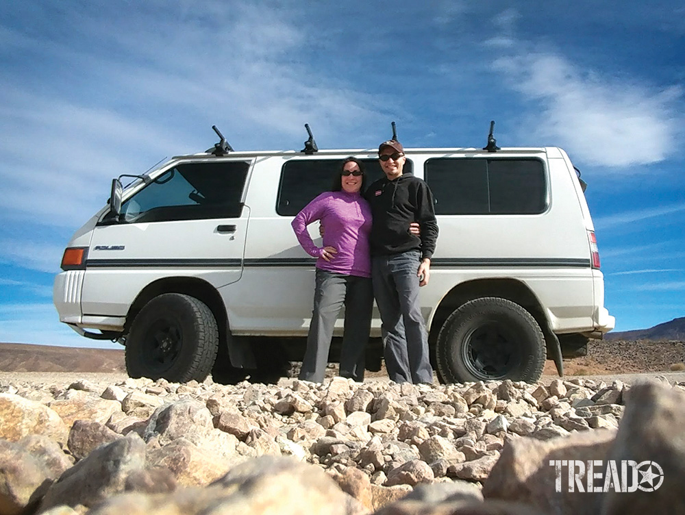 A couple poses in front of their white Mitsubishi Delica van.