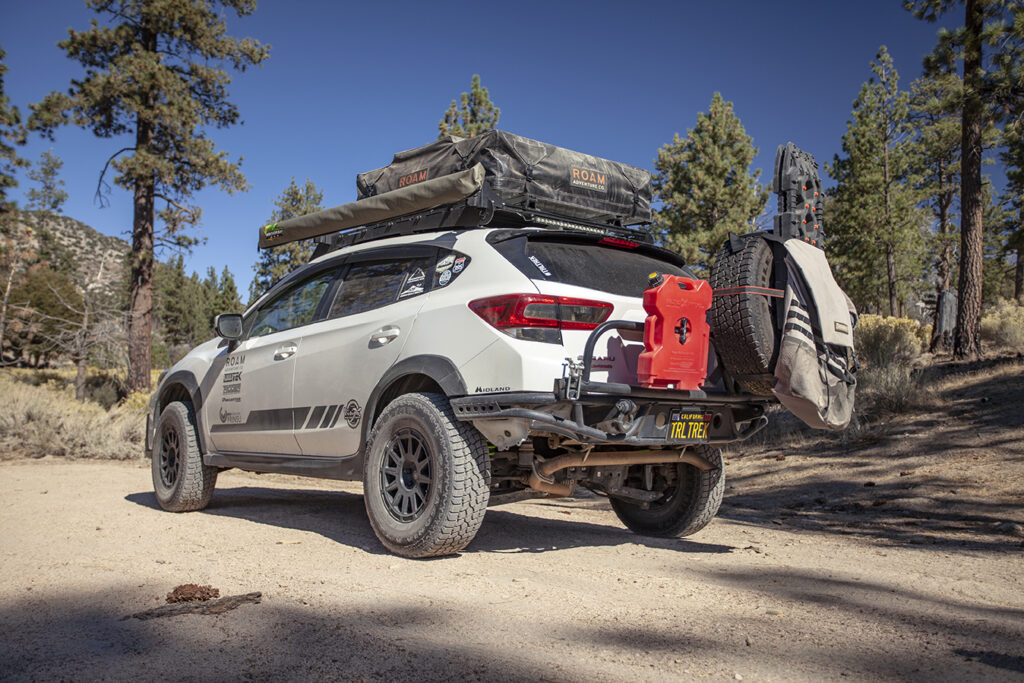 From Tread July/August 2021 a White 2019 Subaru Crosstrek with overland accessories parked on dirt in mountains.