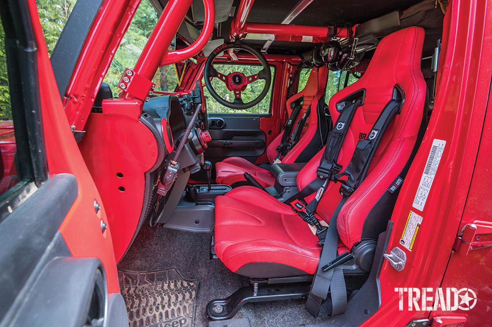 The interior of a red Jeep JKU is all red from the seats to the roll bar.