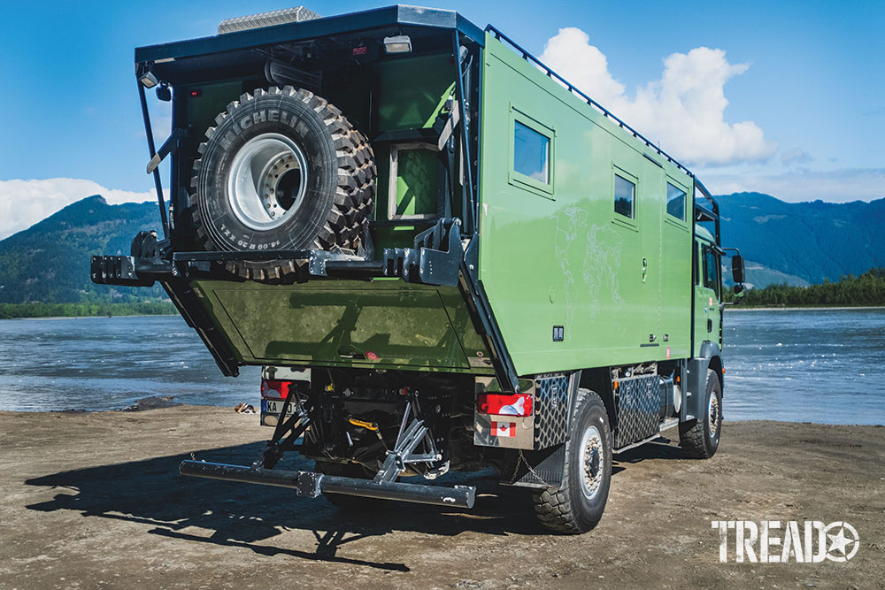 Rear view of the Mint Green MAN Expedition Truck that shows the spare tire and other accessories.