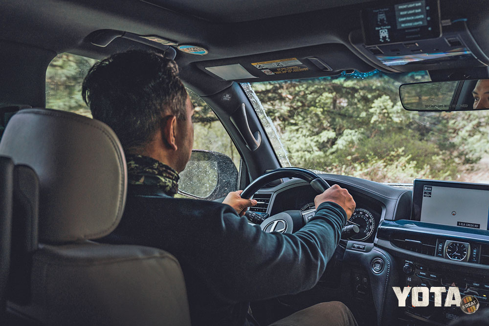 A view from the rear seat shows a man driving the Lexus LX570 and some of the dash.