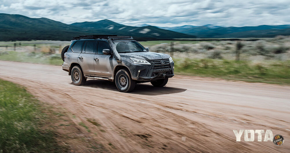 The black Lexus LX570 speeds down a dirt road.