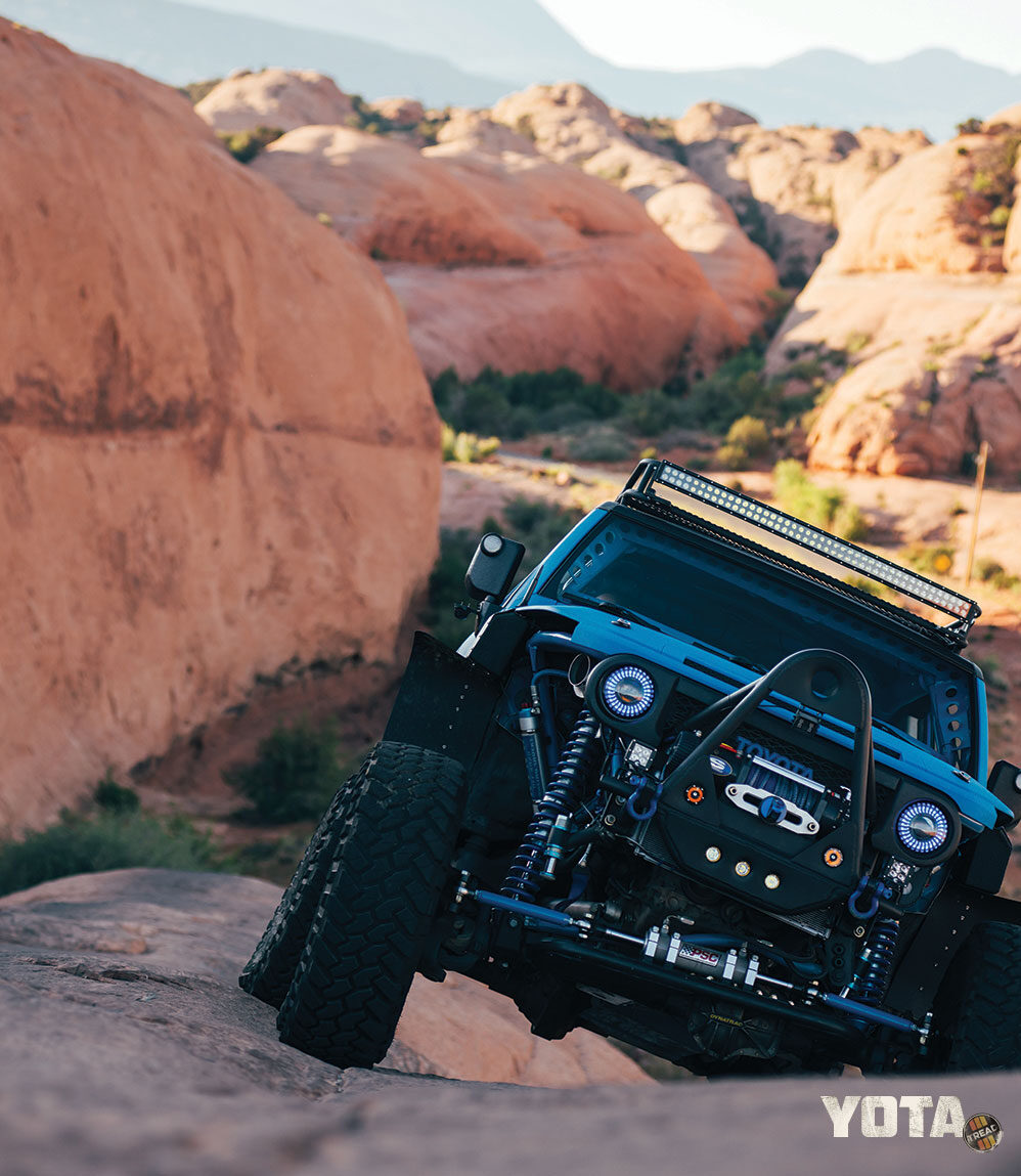 A blue FJ Cruiser climbs the rocks of Moab, Utah.