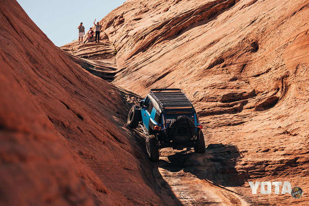 A blue FJ cruiser climbs Hell's Gate in Moab.