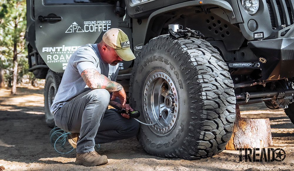Man airs his tires up while parked in dirt.