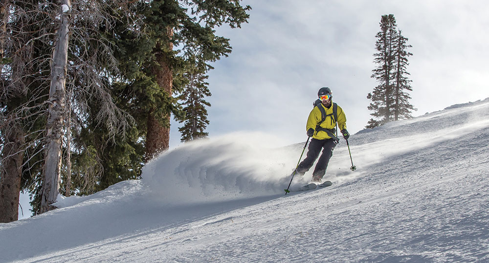 The author skis through fresh powder in his bright yellow coat.