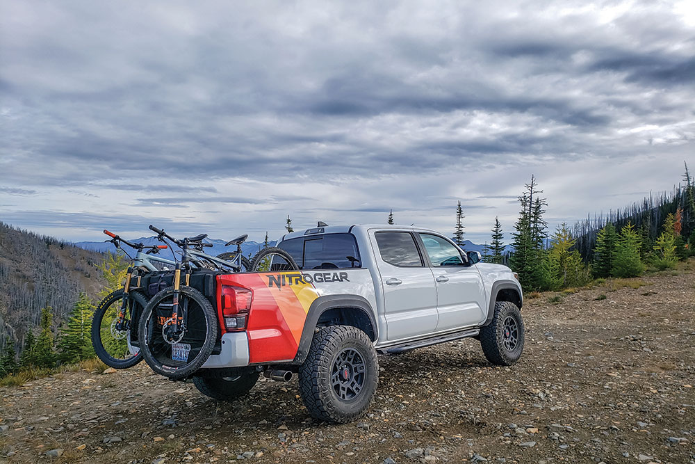 This gray truck hauls bicycles on its tailgate.