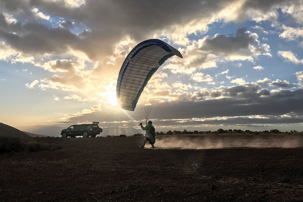 Colin Kemp paraglides past his Toyota vehicle.