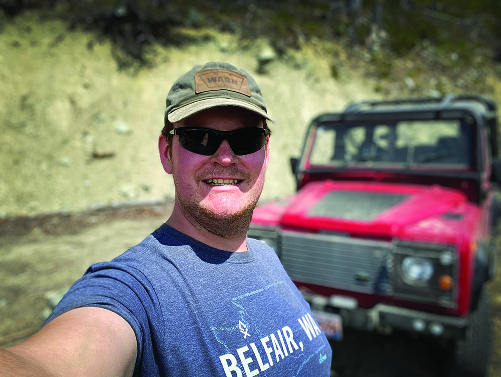 A selfie of the Defender's owner, Nick McKay, smiling, with the vehicle in the background.