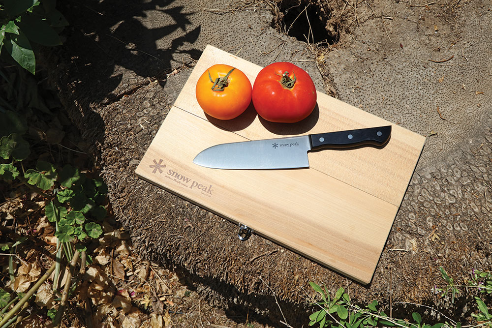 The high carbon knife rests atop the birch cutting board.