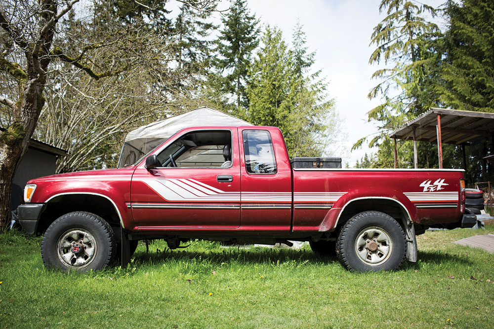 The 1990 Toyota Pickup's paint job, white stripes on the red body paint.