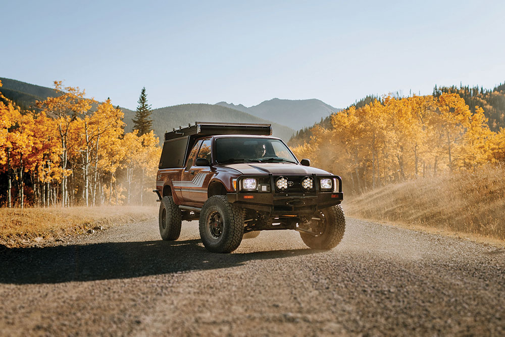 "Little Red" parks on dirt among fall foliage.