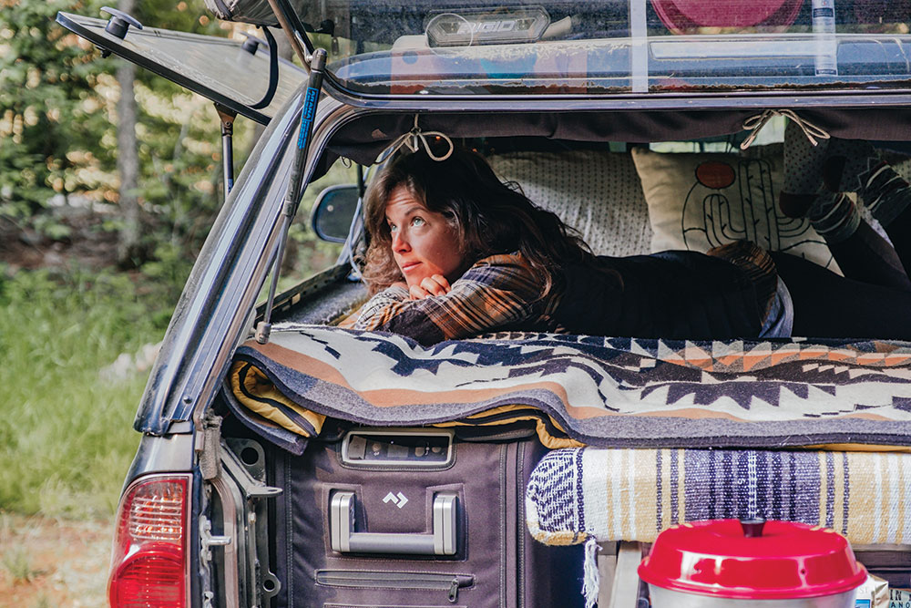 Lizzy rests in the truck bed atop patterned blankets.