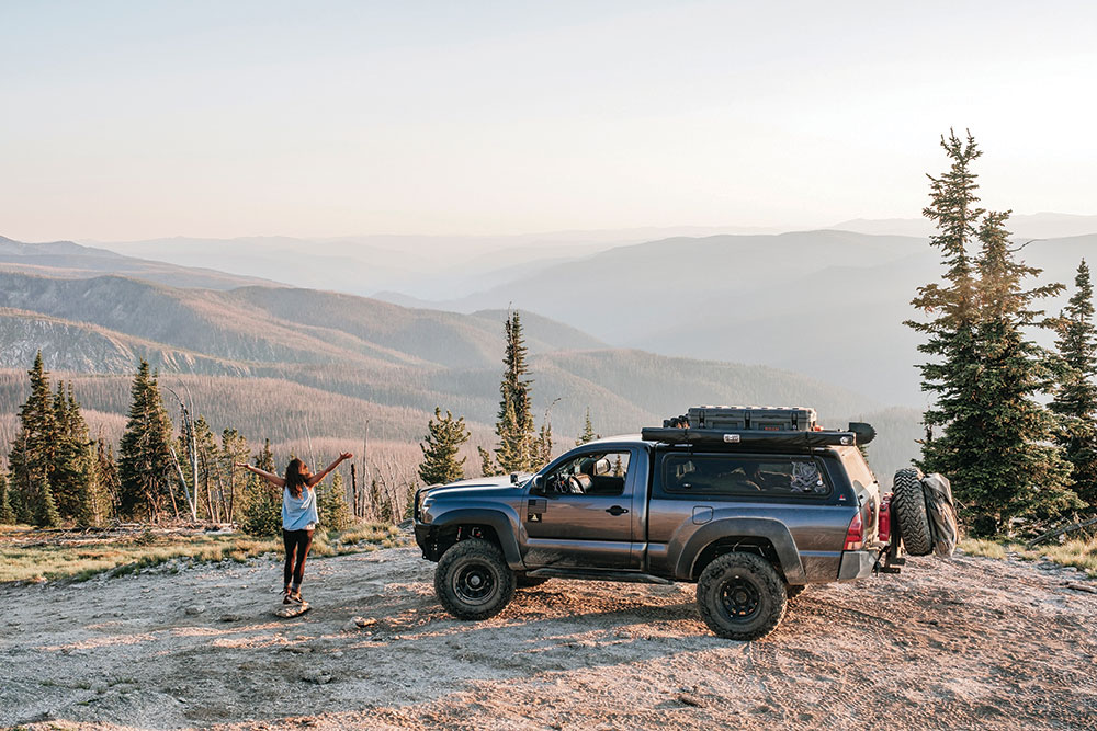 Lizzy and the Tacoma both pose before mountainous scenery at a campsite in Idaho.