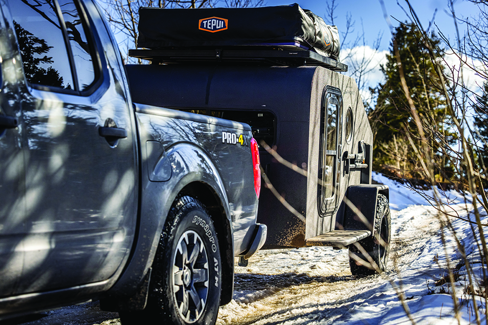 The black exterior of the Campworks NS-1 trailer stands out in a snowy landscape. 