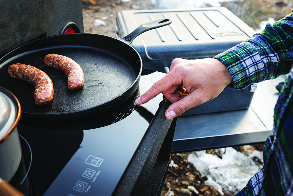 Cooking sausages in cast iron on the camper's induction cooktop.