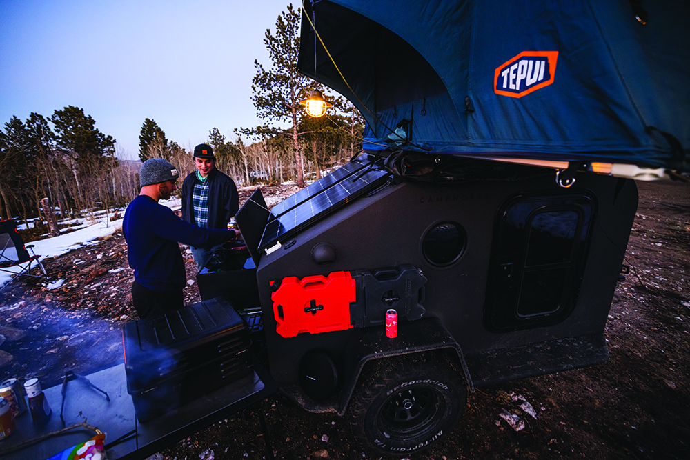 A bright red jerry can stands out when strapped to the side of the black camper.