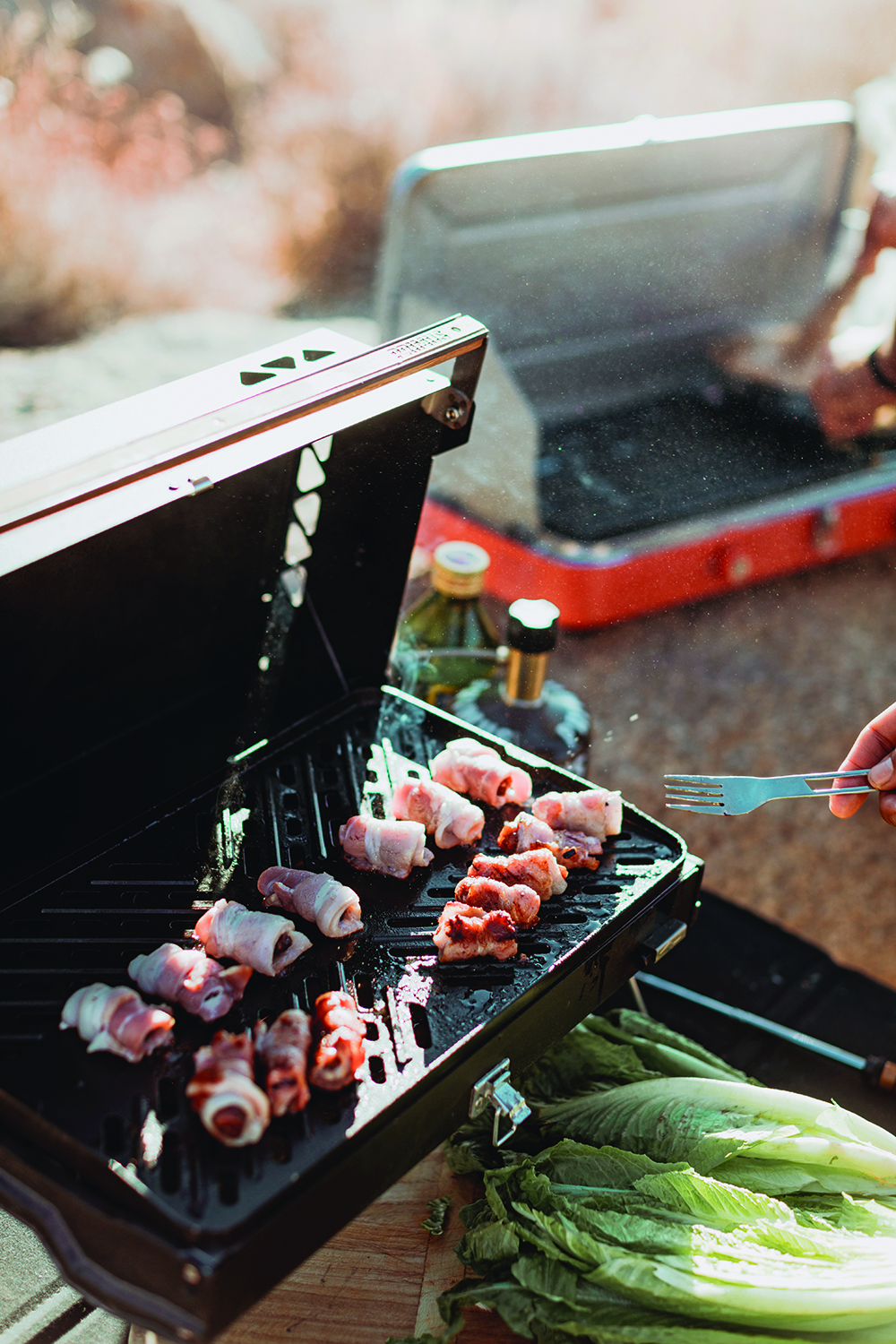 Gas camp grill with bacon on it 