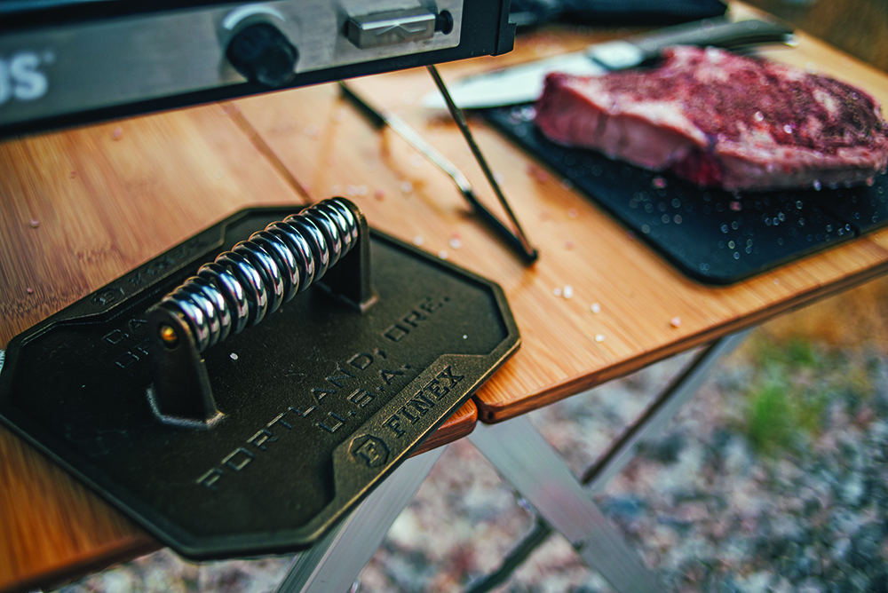 Grill press ready to be used on a steak.