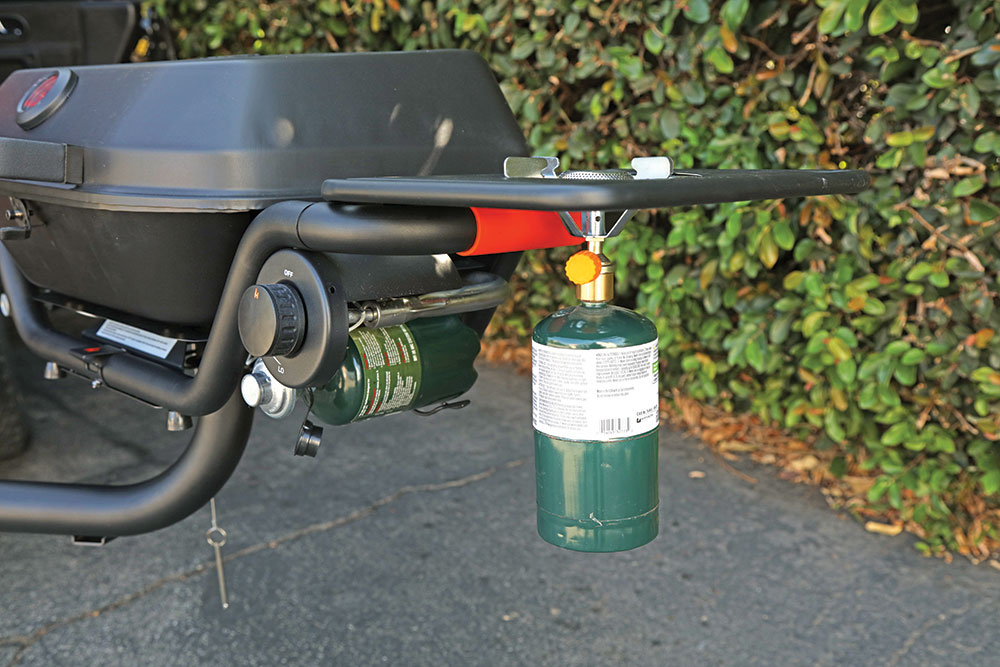 A smaller 1-pound propane tank is attached to the bottom of a side grill to a Hitchfire Grill.