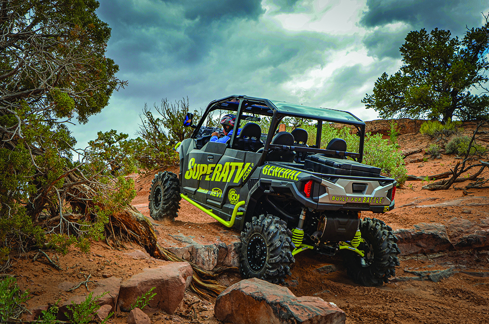 SuperATV black and green side-by-side drives up rocky trail in Moab, Utah.