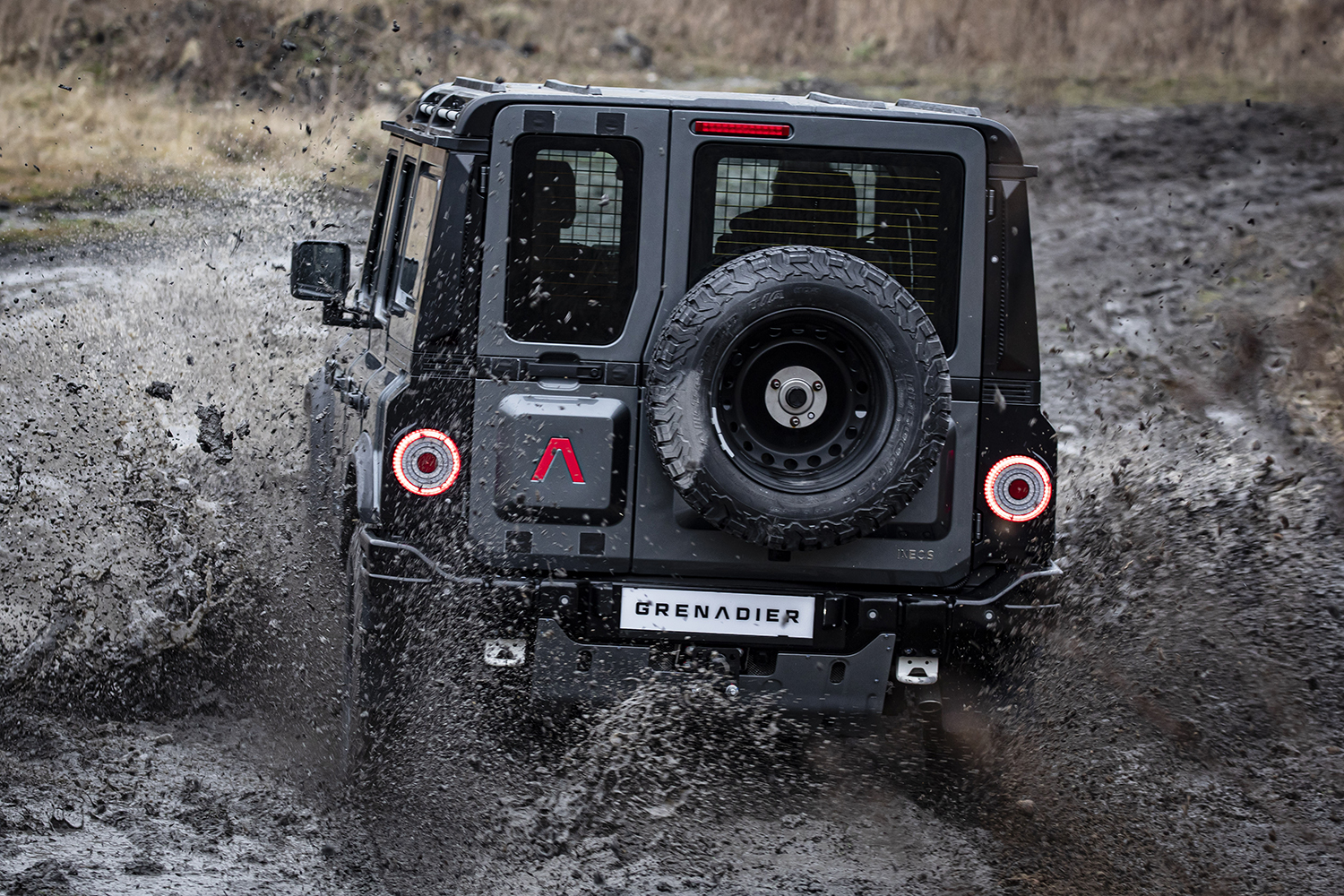 Black SUV drives through mud hole.