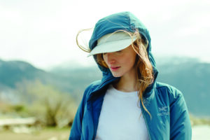 A woman wears a blue hooded performance jacket.