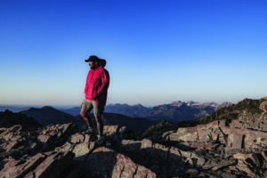 This hiker's bright clothing makes him stand out against a blue sky.