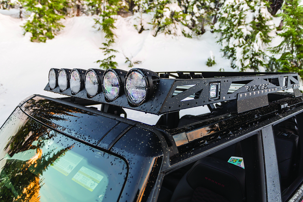 Black roof rack and 6 front lights rest atop the roof of the Bronco build.