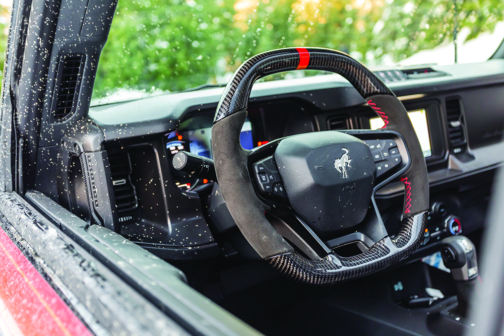 Mud-splattered leather-wrapped Bronco steering wheel.