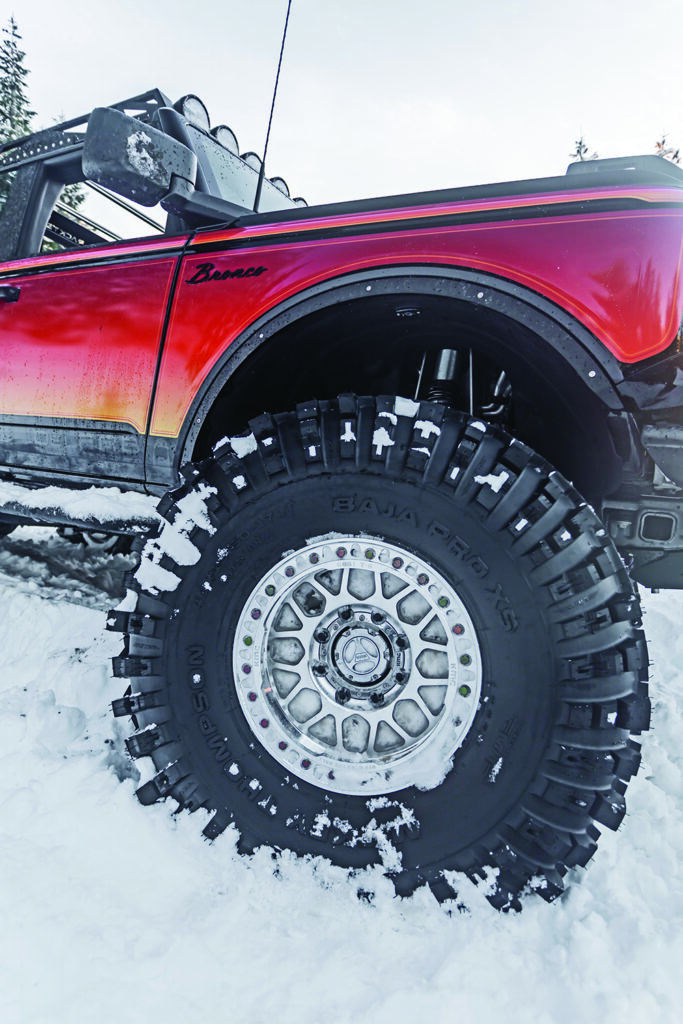 Large tries and chrome wheels stand out against the orange wrap on the Bronco.