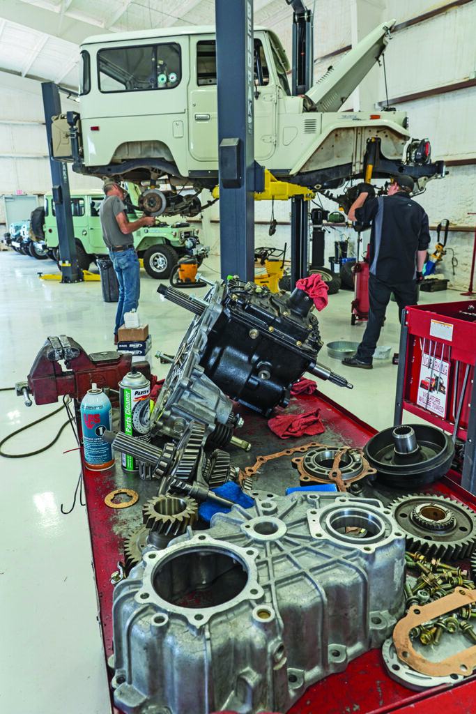 Overland Cruisers garage, full of vehicle parts and a Land Cruiser on a lift.