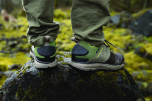 A hiker in performance sneakers stands atop a rock.