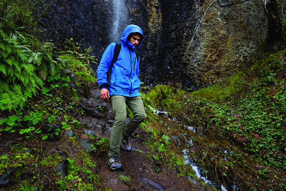 A man walks downhill in performance hiking clothing.