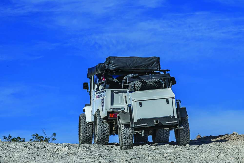 The 1988 Toyota Bandeirante tows a trailer through rocks.