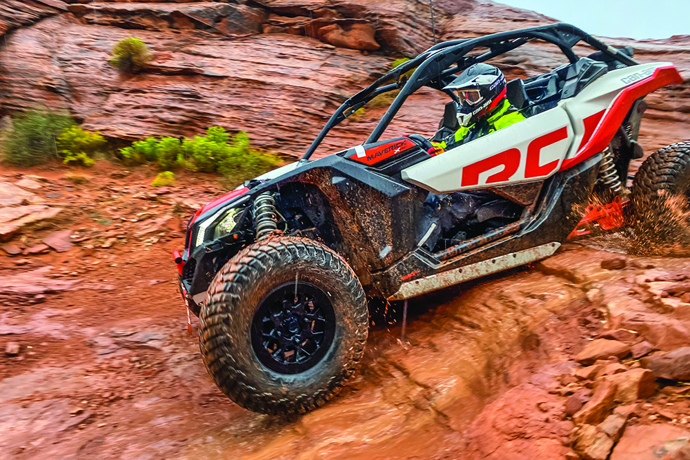 A red, gray, and black UTV rolls downhill.