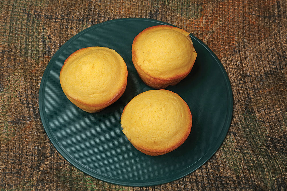 Three yellow corn muffins rest on a blue plate.