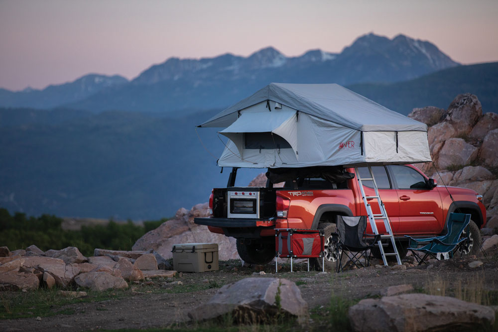 A red truck with roof top tent parks for the night.