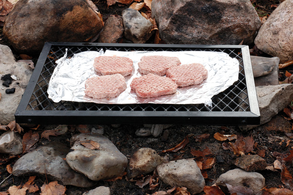 Campsite cuisine like pork chops cook well on a grate above hot coals.
