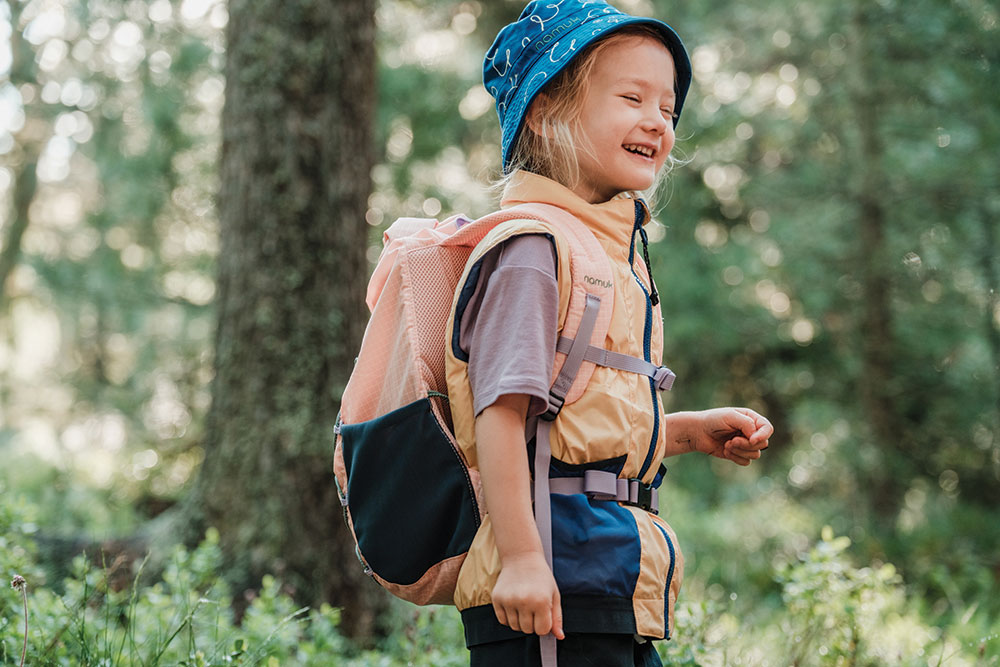 namuk / Spring Collection child laughing with a blue hat and backpack 