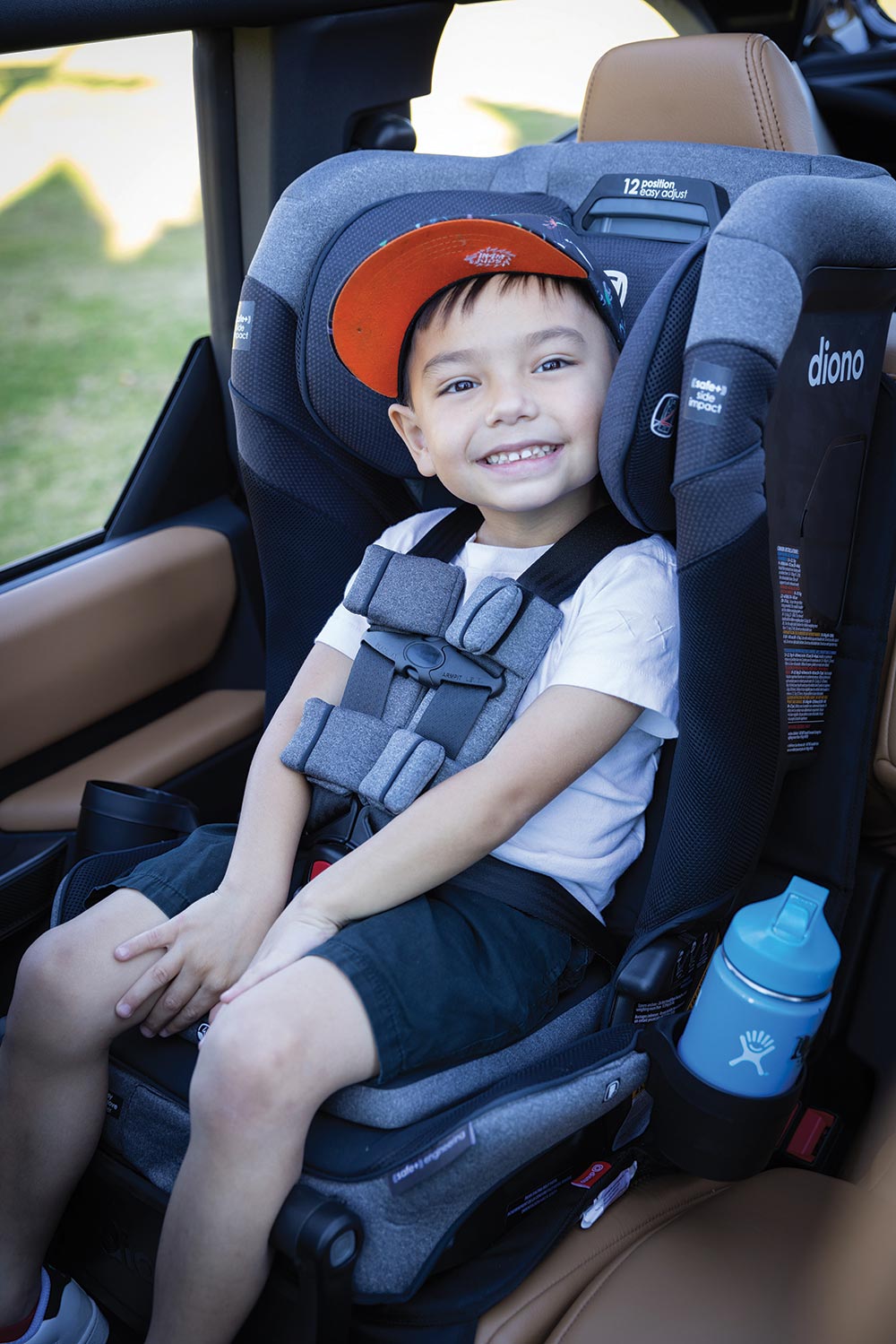 A little boy smiles at the camera in a carseat family gear