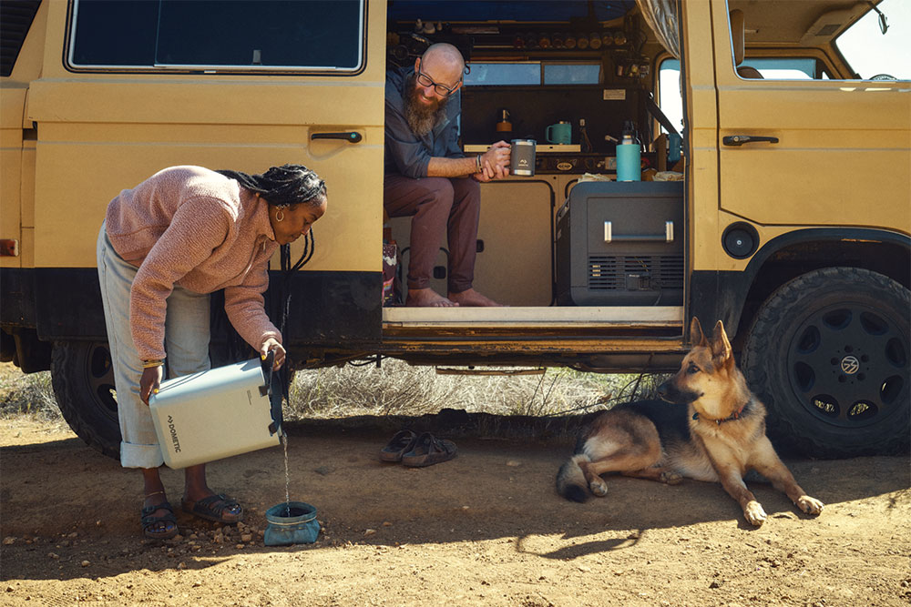 A woman fills her dog's bowl with the water jug.