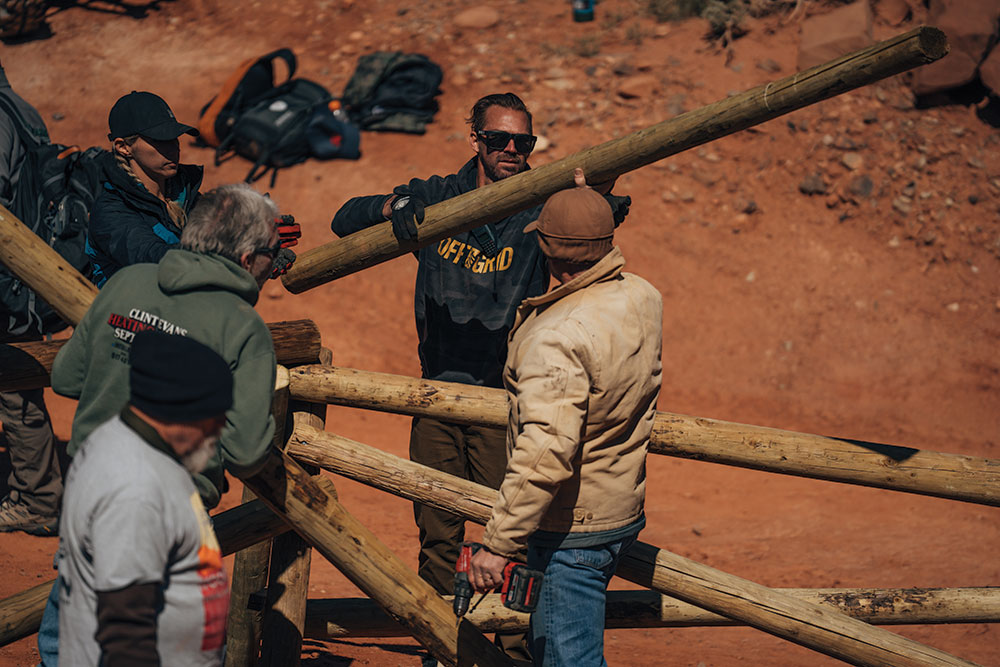 A group of men arrange fence poles in the desert.