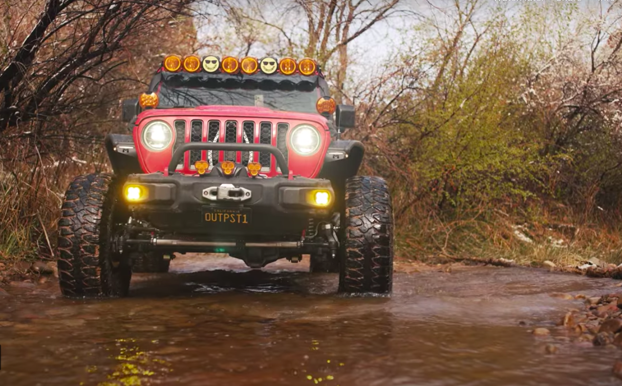 Red Jeep drives through creek on Steal Bender Trail in Moab, Utah.