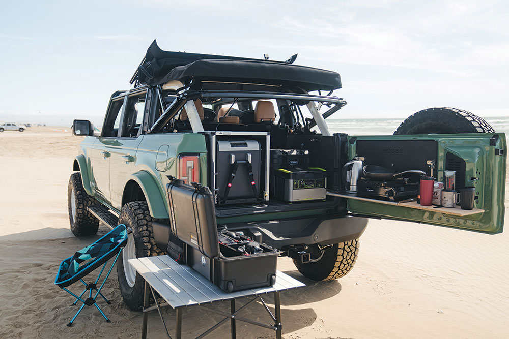 The rear plate system, icebox slide-out, and tailgate table are a compact camp kitchen setup.
