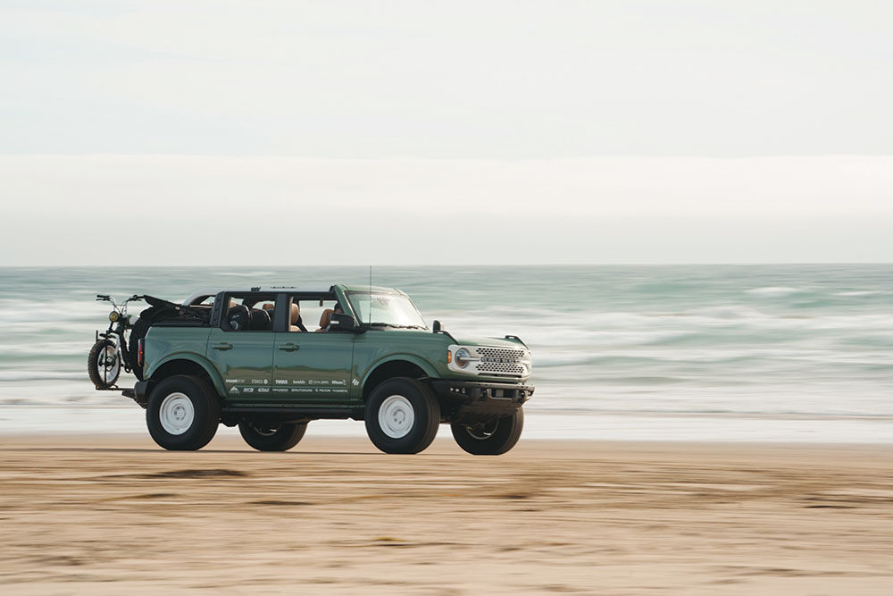The green Bronco accelerates quickly down the beach.