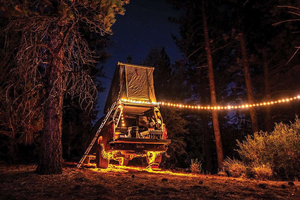 The Tundra at night, lit up but a string of Christmas lights that hang below the roof top tent.