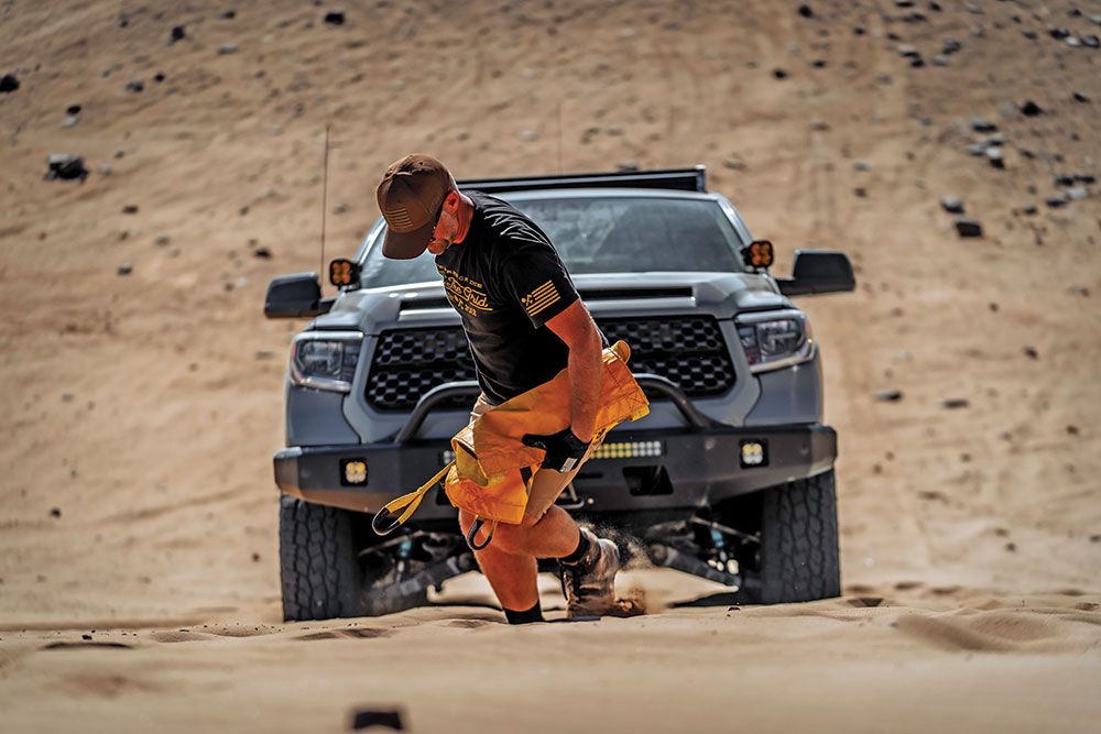 Samuel walks ahead of the truck holding the Deadman Offroad anchor.