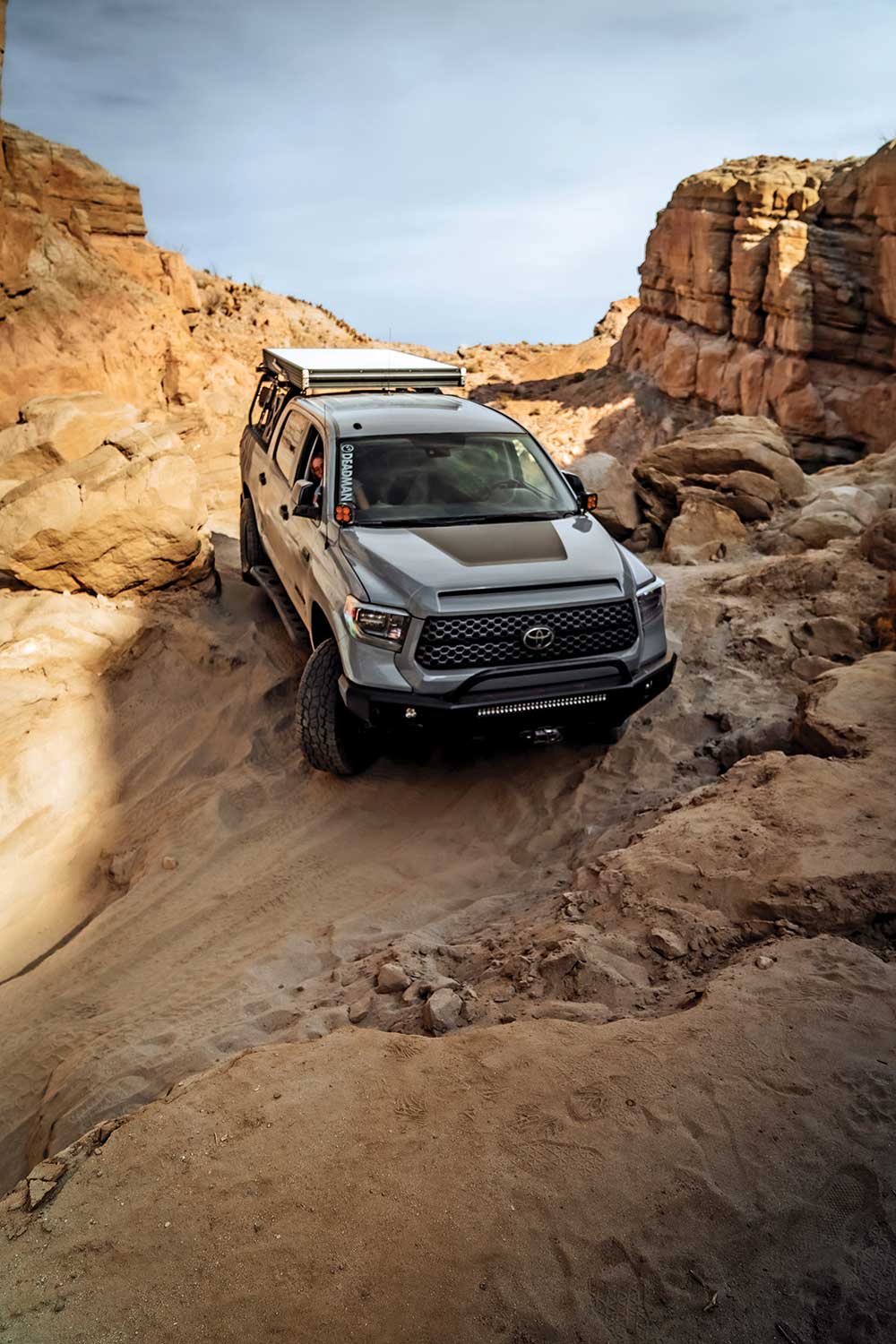 The gray Tundra rolls downhill through desert rocks.